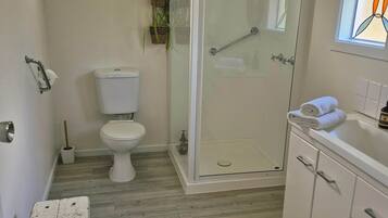 A modern bathroom with a glass shower enclosure, a toilet, and a sink with a towel on the counter.