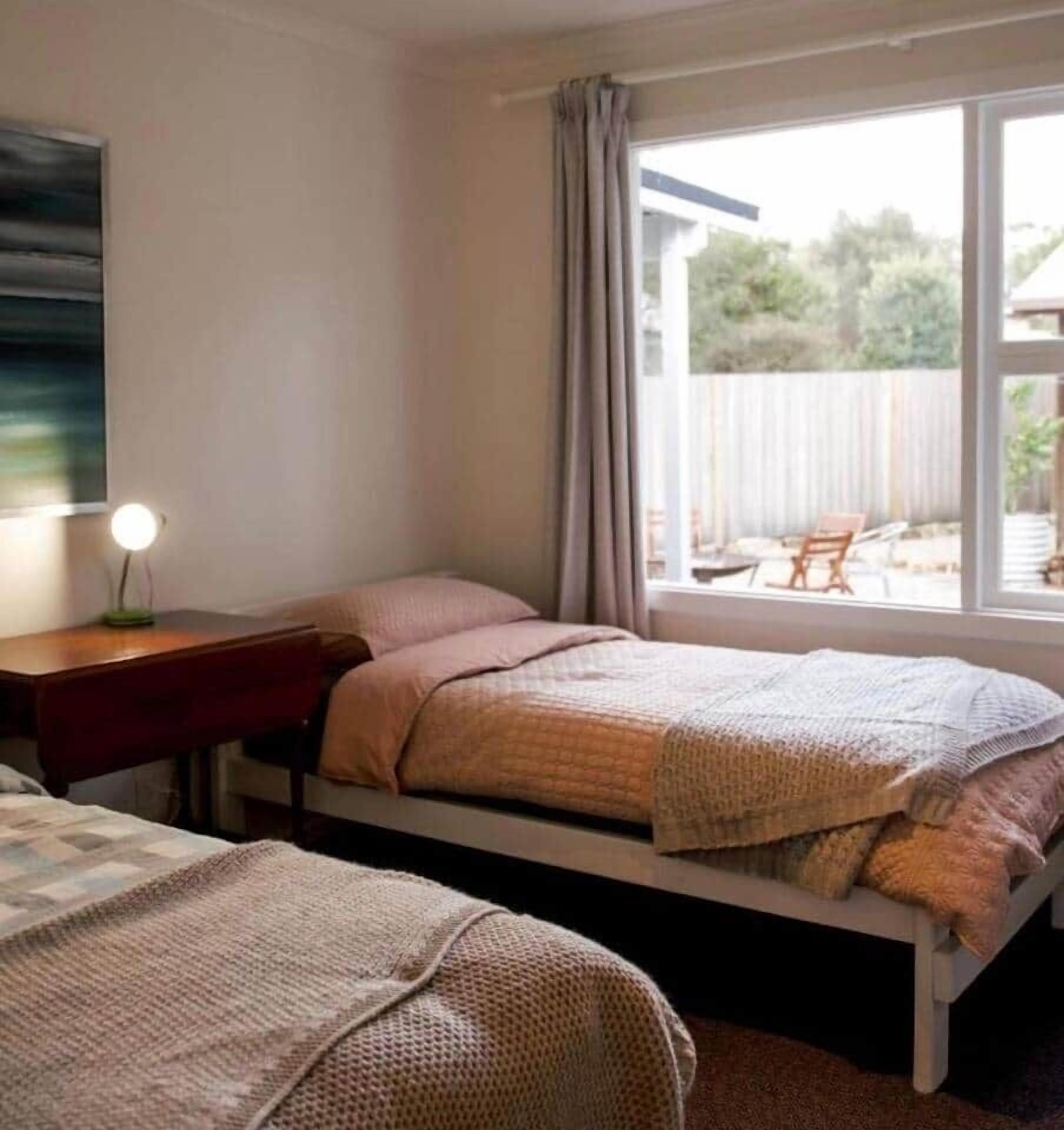 Ein Schlafzimmer mit zwei Betten, einem Schreibtisch und einem Fenster mit Vorhängen.