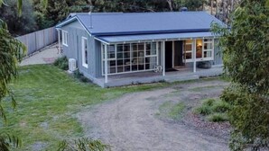 Une maison de plain-pied dotée d’un grand porche vitré, entourée d’une allée en gravier et d’une clôture en bois.