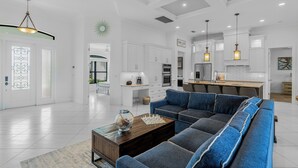A spacious living room with a sectional sofa, a coffee table, and a chandelier.