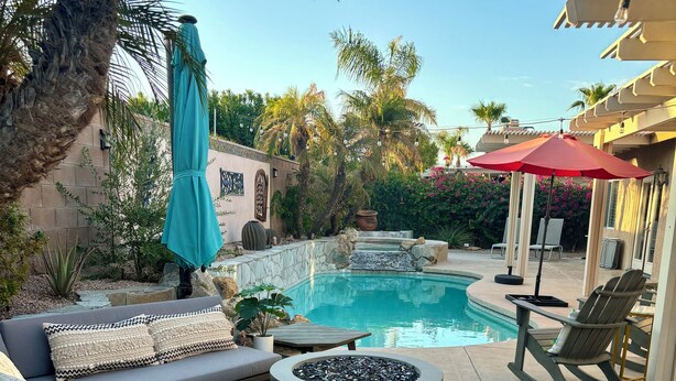 A pool area with a stone fire pit, lounge chairs, and a covered seating area. - Luxury Desert 3BR house with Private Pool & Spa (La Quinta)