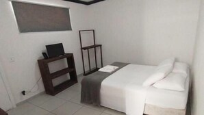 Una habitación pequeña y limpia con cama, escritorio y ventilador de techo.