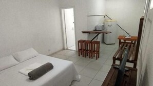 Habitación de hotel con cama, escritorio, silla, microondas y ventilador de techo.