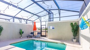 A swimming pool with a glass ceiling, lounge chairs, and potted plants. - Spacious 4-bedroom townhome, perfect for family getaways! (Kissimmee)