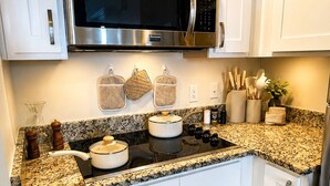 A kitchen with white cabinets, a stainless steel microwave, granite countertops, and a built-in oven. - Tan Haven-A Chic & Cozy Modern Getaway (Fort Myers)