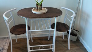 A round dining table with two chairs, a small vase with flowers, and a floor lamp. - Tan Haven-A Chic & Cozy Modern Getaway (Fort Myers)