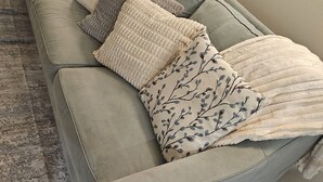 A grey sofa with multiple cushions, a patterned throw blanket, and a patterned rug. - Tan Haven-A Chic & Cozy Modern Getaway (Fort Myers)