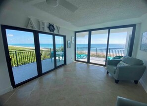 Un balcon spacieux offrant une vue sur l’océan, un fauteuil confortable et une grande porte-fenêtre coulissante.