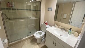Ein Badezimmer mit Duschkabine, Toilette und Waschtisch mit Waschbecken und Spiegel.