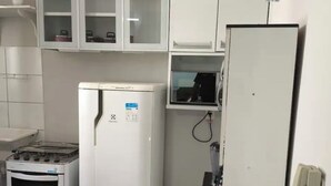 Una cocina compacta con armarios blancos, un refrigerador, una estufa y un microondas.