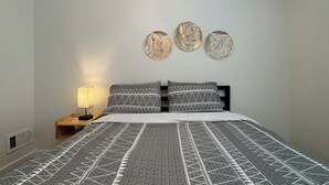 Ein Schlafzimmer mit einem Bett, einem Nachttisch und drei Wanddekorationen.