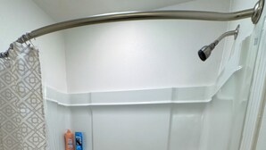 Ein modernes Badezimmer mit barrierefreier Dusche, einer integrierten Ablage für Toilettenartikel und einem Duschvorhang mit geometrischem Muster.