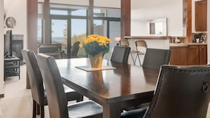 A dining area with a large table, chairs, and a vase of yellow flowers. - Pacific Seas Suite-Wild Pacific Trail, Ocean View! (Ucluelet)
