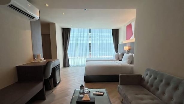 A modern hotel room with a bed, a sofa, a desk, and a coffee table. - The One Cozy Living (Pattaya)
