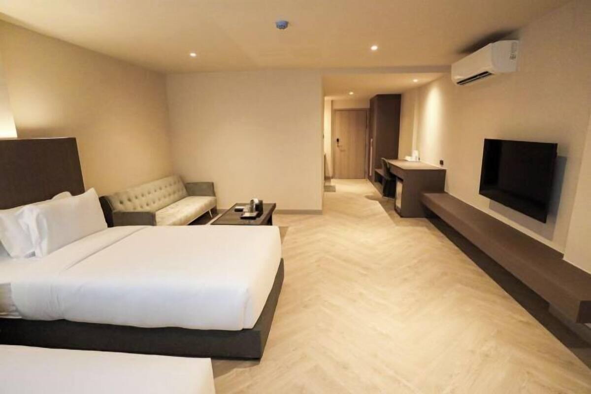 Una habitación de hotel con una cama grande, un sofá, un televisor y un escritorio.