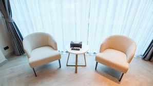 A room with two armchairs, a small round table, and a box of tissues. - The One Cozy Living (Pattaya)