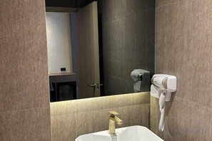 A bathroom with a white sink, a hairdryer, and a mirror. - The One Cozy Living (Pattaya)