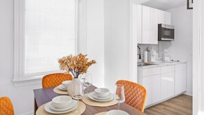 Cocina moderna con armarios blancos, microondas y pileta.