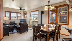 A dining area with a wooden table and chairs, a ceiling fan, and large windows offering a view of mountains. - Downtown Winter Park Area Condo H-201 I Great Views I Bunk Room I Discounted Attractions (Fraser)