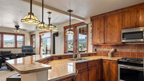 A kitchen with wooden cabinets, a stainless steel oven, and a granite countertop. - Downtown Winter Park Area Condo H-201 I Great Views I Bunk Room I Discounted Attractions (Fraser)