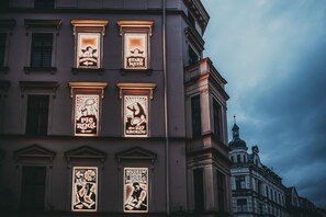A building with illuminated signs advertising various establishments, including a museum and a pie shop. - Family Loft With Mezzanine Old Town (Torun)