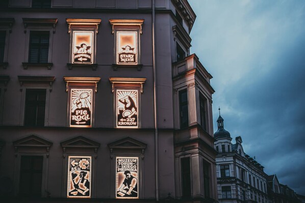 Un immeuble orné d’enseignes lumineuses qui font la publicité de divers commerces, notamment un musée et une boutique de tartes.