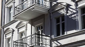 A multi-story building with a classical architectural style, featuring balconies with ornate metal railings and large windows. - Family Loft With Mezzanine Old Town (Torun)