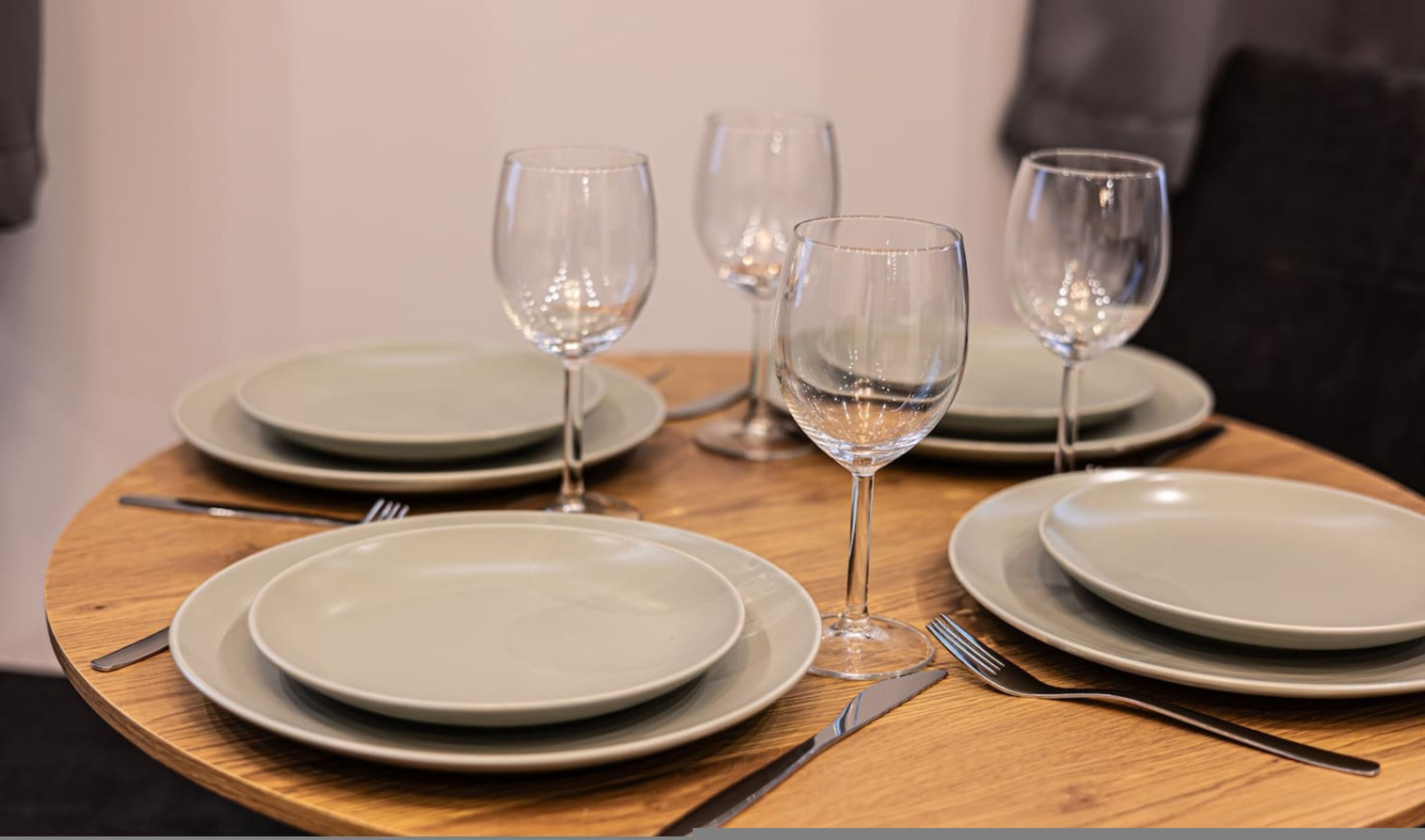 A table set with plates, cutlery, and wine glasses.