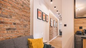 Un intérieur moderne avec un mur en briques, un canapé gris agrémenté d’un coussin jaune et une petite table sur laquelle repose un livre.