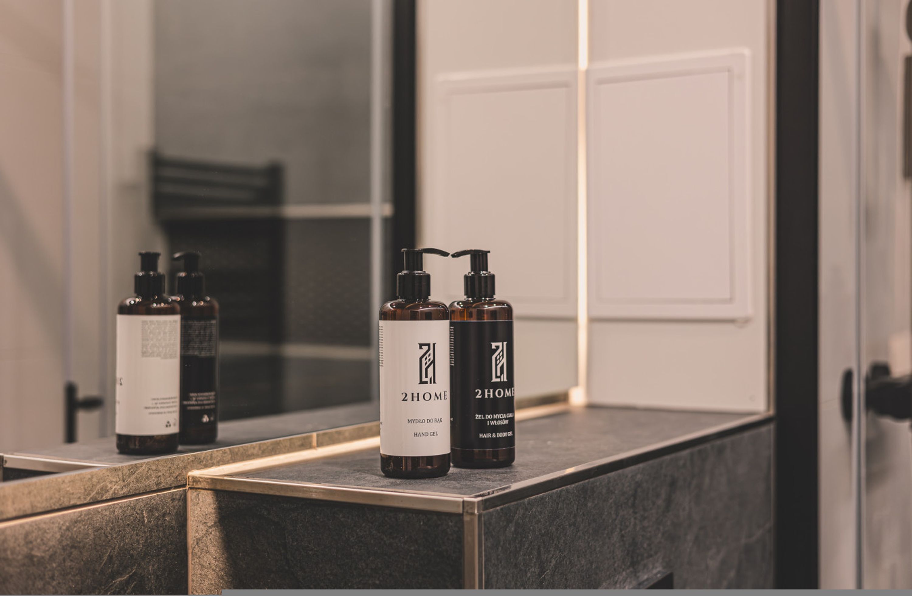 Un ripiano del bagno con tre flaconi di gel per le mani 2HOME.