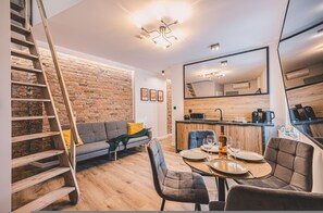 A modern apartment with a loft-style kitchen, a dining area, and a living room with a brick wall and a staircase. - Estrella 14 - Loft z Dusz w Centrum Toru Skiej Star wki (Torun)