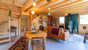 Ein gemütliches Blockhaus-Interieur mit einem Holzesstisch, einer Couch, einem Bücherregal und einem Kamin.