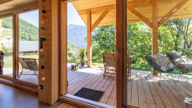 Eine Holzterrasse mit Sitzgelegenheiten und Blick auf eine gebirgige Landschaft.