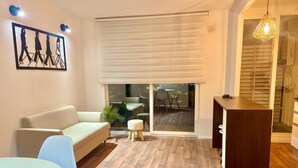 A modern living room with a sofa, a dining table, and a kitchen area with a counter and stools. - Beautiful apartment with excellent volcano and lake view. (Villarrica)
