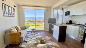 A modern apartment with a living room, a balcony with a view, a kitchen, and a dining area. - Beautiful apartment with excellent volcano and lake view. (Villarrica)