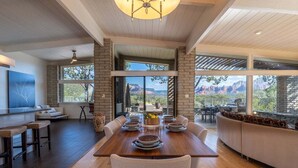 A dining area with a wooden table, chairs, and a view of mountains through large windows. - New Listing Vast Red Rock Views 2 Master Suites - Panorama Landing (Sedona)