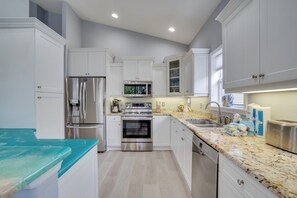 A modern kitchen with white cabinetry, stainless steel appliances, and a granite countertop.