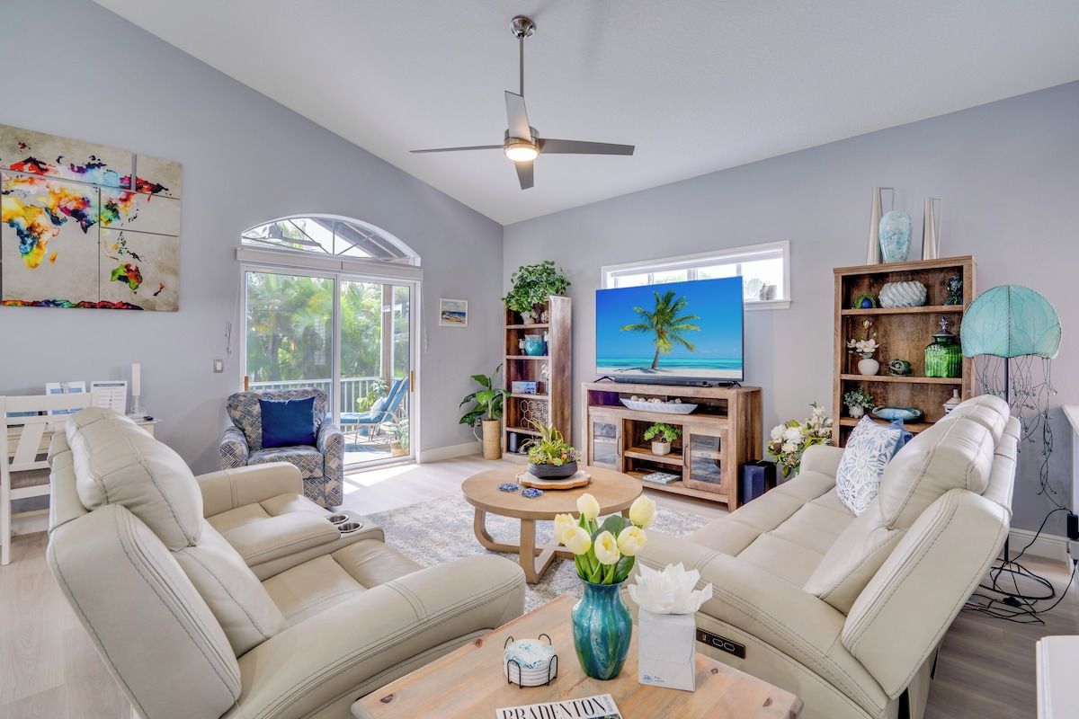 A modern living room with a television, comfortable seating, a coffee table, and a bookshelf.