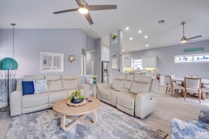 A modern living room with a sectional sofa, a coffee table, and a dining area with a table and chairs. - Griffins' Island Getaway (Holmes Beach)