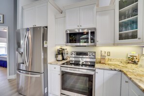 A modern kitchen with stainless steel appliances, white cabinetry, and a granite countertop.