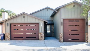 Un garage pour deux voitures, attenant à une maison dont les fondations sont en briques et l’entrée en pierre.