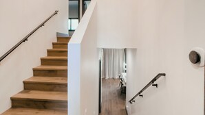 Un escalier avec des marches en bois et des rampes en métal, menant à une pièce comprenant un coin repas.