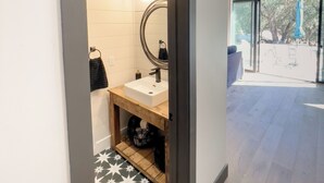 Une salle de bain moderne avec un lavabo blanc, un miroir et un porte-serviettes.