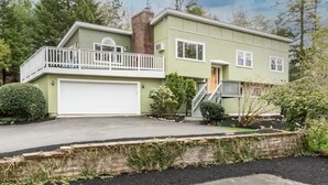 A two-story house with a front garage, a balcony on the upper floor, and a small front yard with landscaping. - Manchester by the Sea l Fireplace l King Bed (Manchester-by-the-Sea)