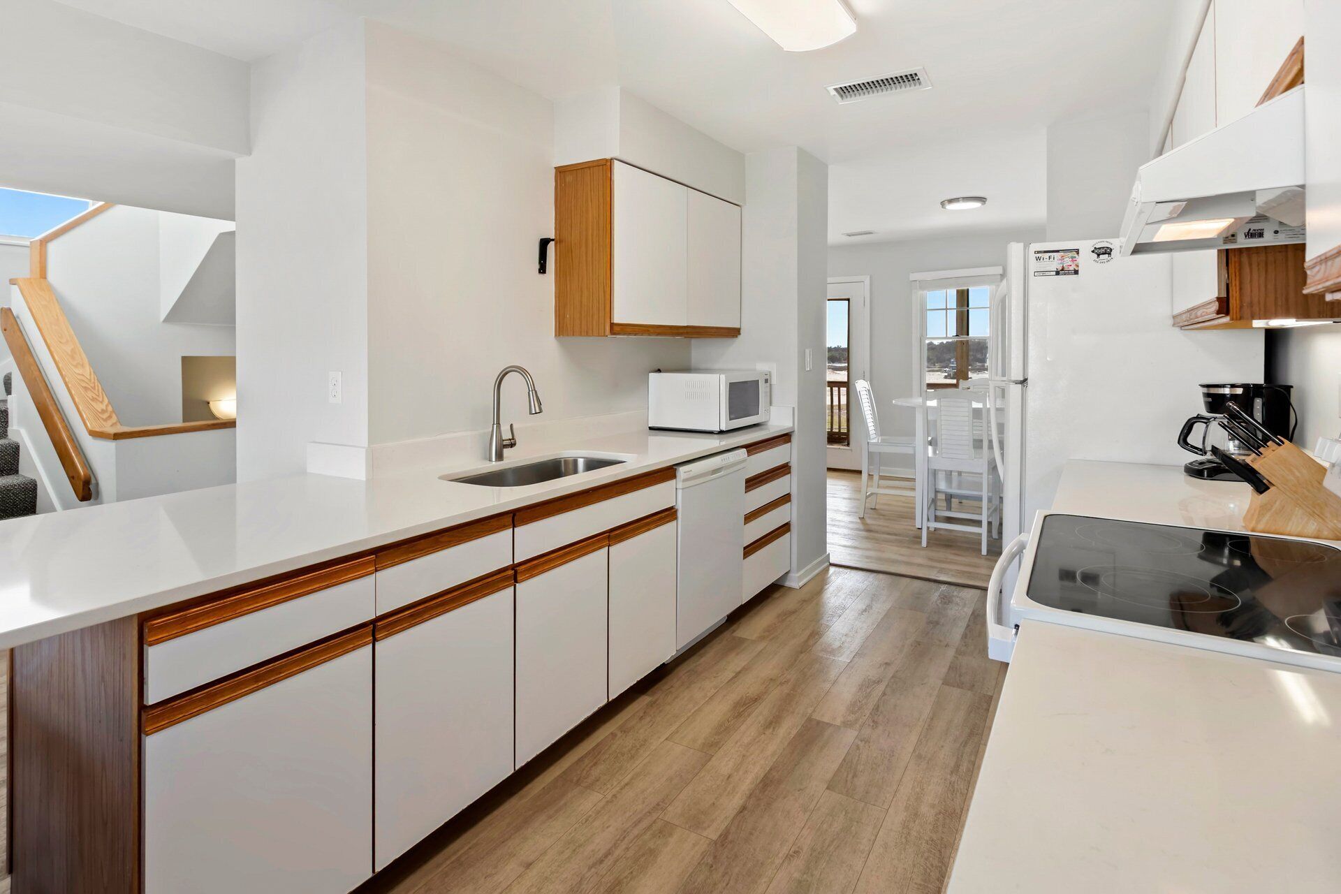 A modern kitchen with white cabinetry, a built-in microwave, and a stainless steel sink.
