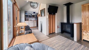 Ett kompakt bostadsutrymme med ett litet kök, en tv, en öppen spis och en soffa.