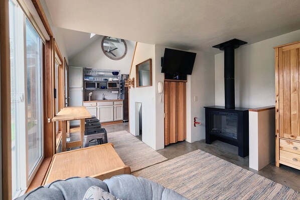 A compact living space with a kitchenette, a television, a fireplace, and a sofa.