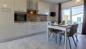 Une cuisine moderne avec un coin repas, comprenant un four encastré, un téléviseur à écran plat et une table à manger avec des chaises.