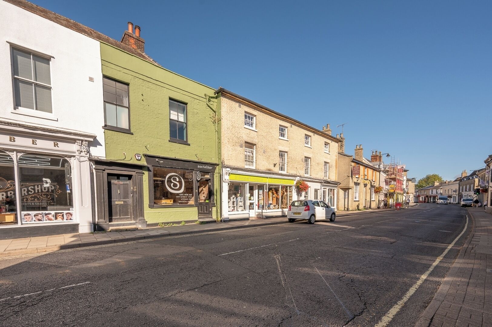 A street with various shops, including a barber shop and a social bar.