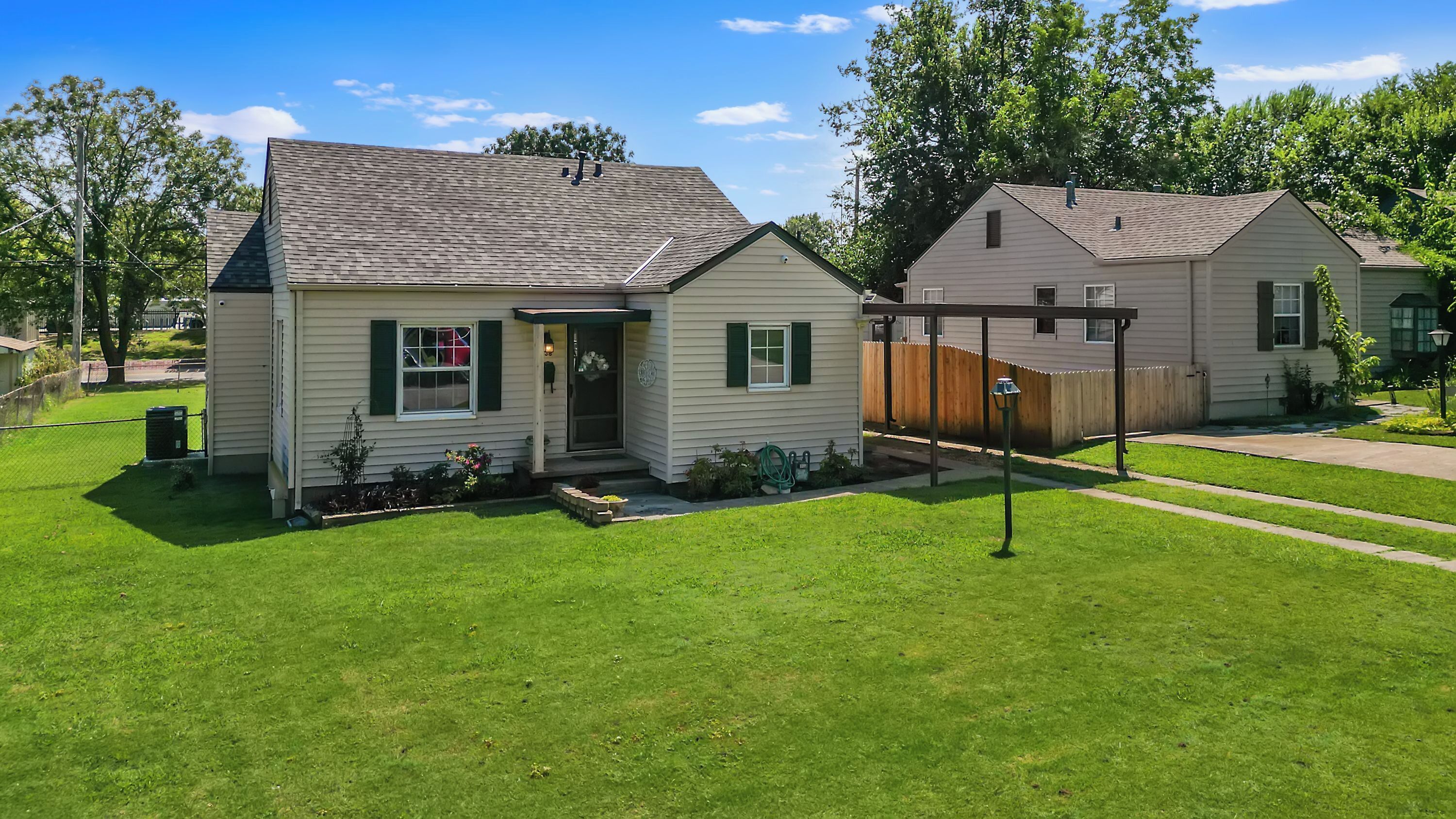 A two-story house with a front porch, a fenced backyard, and a well-maintained lawn.